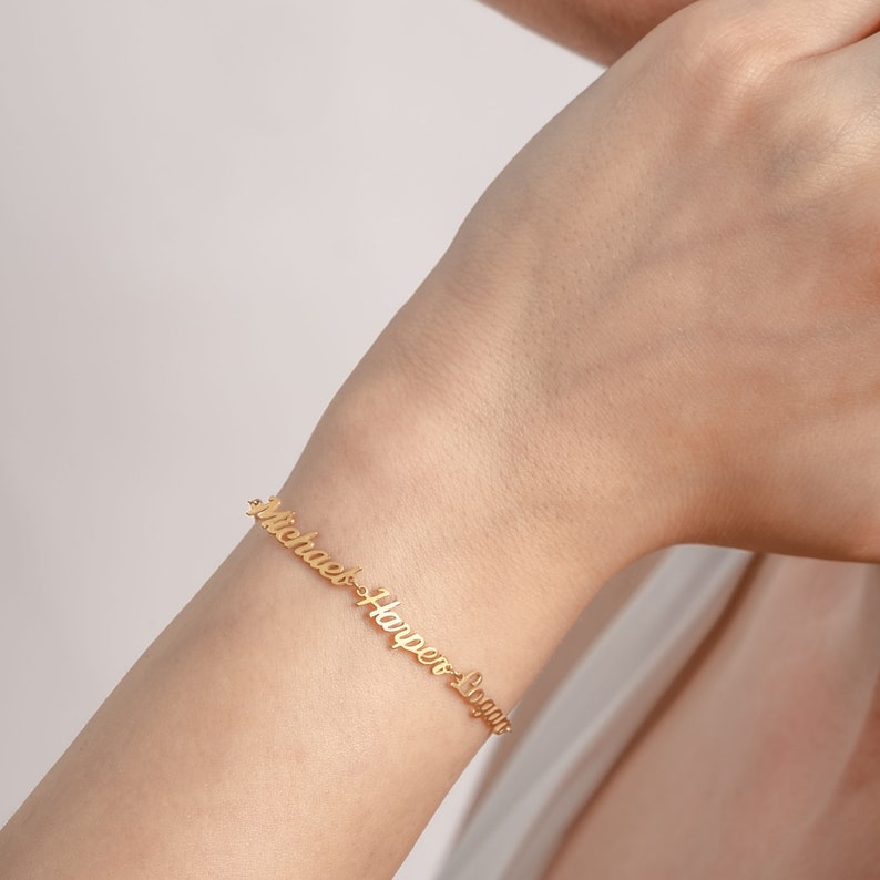 May include: Gold bracelet with the names "Michael", "Harper", and "Logan" engraved on it.