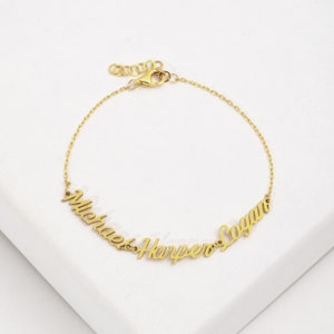 May include: Gold chain bracelet with three names, "Michael", "Harper", and "Logan", spelled out in cursive.
