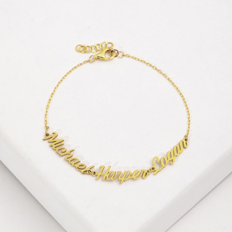 May include: Gold chain bracelet with three names, "Michael", "Harper", and "Logan", spelled out in cursive.