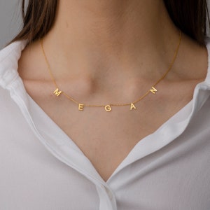 May include: A gold necklace with the name "Megan" spelled out in individual letters hanging from the chain.
