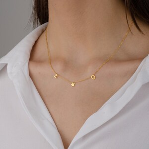 May include: A gold chain necklace with a star charm and letter charms "L" and "O".