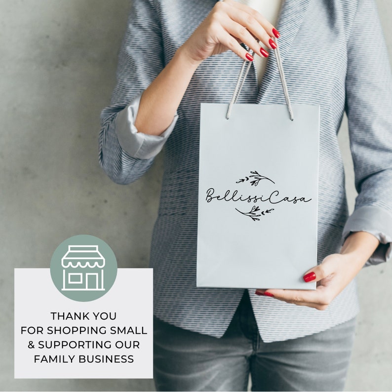 May include: A person holding a white shopping bag with the text "Bellissima Casa" and a floral design. The bag has a green and white store icon and the text "Thank you for shopping small & supporting our family business".