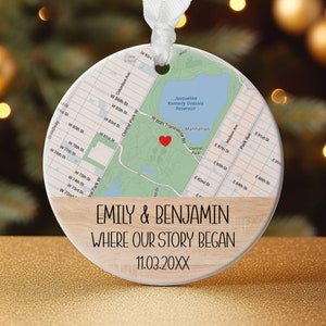 May include: A round Christmas ornament featuring a map of Manhattan, with a red heart marking a location. The ornament includes the text "EMILY & BENJAMIN WHERE OUR STORY BEGAN 11.03.20XX" and a light wood grain design.