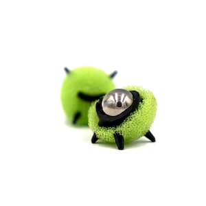 May include: Two green and black spiky toys with a silver ball in the center of one.