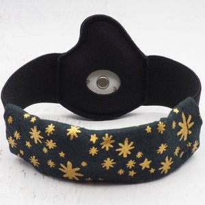 Op de afbeelding: Zwart hoofdband met een gouden sterrenpatroon en een kleine zwarte sensor aan de achterkant.