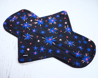 May include: A black reusable cloth menstrual pad with a blue and pink starburst pattern.