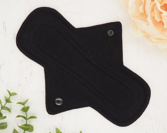 May include: Black reusable cloth menstrual pad with snap closures.