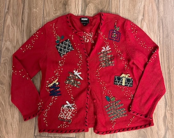 May include: Red Christmas cardigan with a button-up front and a variety of festive embellishments, including presents, bows, and snowflakes. The cardigan is made of a soft, knit fabric and has a relaxed fit.