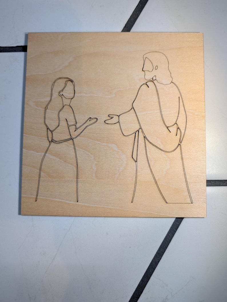 Pode incluir: Uma placa de madeira clara de formato quadrado com um desenho de linha preta de uma pessoa com cabelo comprido em frente a uma figura de t&uacute;nica com cabelo pelos ombros. As duas figuras est&atilde;o viradas uma para a outra com as m&atilde;os estendidas.