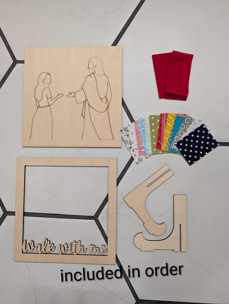 Pode incluir: Um kit de artesanato em madeira com um painel quadrado com uma ilustra&ccedil;&atilde;o de linhas de duas figuras, uma moldura quadrada com o texto "Walk with me", duas pe&ccedil;as de suporte em madeira, dois peda&ccedil;os de tecido vermelho e retalhos coloridos.