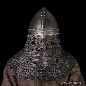 May include: A medieval helmet with a chainmail coif. The helmet is made of metal and has a pointed top. The coif is made of metal rings linked together. The helmet and coif are both silver in color.