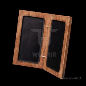 Può includere: Un portamenù in legno incernierato con due pannelli rettangolari neri tipo lavagna incorniciati in legno marrone naturale. I due pannelli sono collegati al centro da due piccoli passanti in corda chiara che permettono di aprire la cornice.