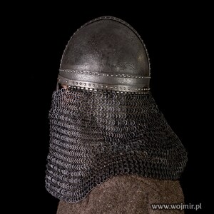 May include: A medieval helmet with a chainmail coif. The helmet is made of metal and has a rounded top. The coif is made of metal rings linked together. The helmet and coif are both dark gray in color.
