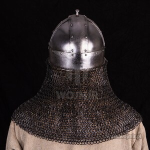 Puede incluir: Un casco de plata con una cota de malla. El casco tiene una parte superior redondeada y est&aacute; decorado con remaches. La cota de malla est&aacute; hecha de anillos de metal entrelazados.