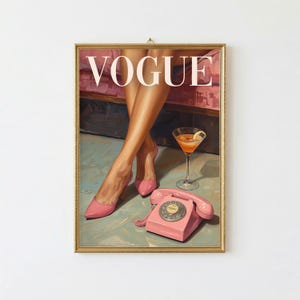 May include: A framed wall art print featuring the word VOGUE in white capital letters. The illustration depicts a pair of legs in pink high-heeled shoes, a stemmed glass filled with an orange liquid, and a vintage pink rotary telephone.