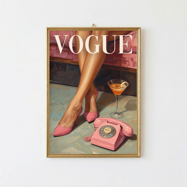 May include: A framed wall art print featuring the word VOGUE in white capital letters. The illustration depicts a pair of legs in pink high-heeled shoes, a stemmed glass filled with an orange liquid, and a vintage pink rotary telephone.