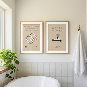 May include: Two rectangular wall art prints in light wood frames. The left print features the text "PLEASE WASH YOUR HANDS BEFORE YOU GO" with a graphic arrow. The right print displays the text "WATER WORKS" with a faucet graphic and "£150".
