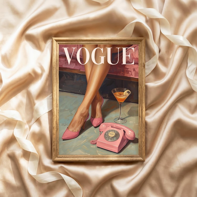 May include: A framed print featuring the word VOGUE in white capital letters. The artwork depicts a pair of legs in pink high-heeled shoes, a martini glass with an orange liquid, and a pink rotary telephone on a light blue floor surface.