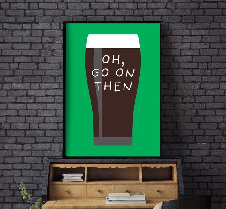 Puede incluir: Un cuadro enmarcado con un fondo verde que representa una pinta de cerveza oscura. El vaso est&aacute; lleno de un l&iacute;quido marr&oacute;n oscuro y coronado con espuma blanca. Las palabras "OH, GO ON THEN" est&aacute;n impresas en blanco en el vaso.