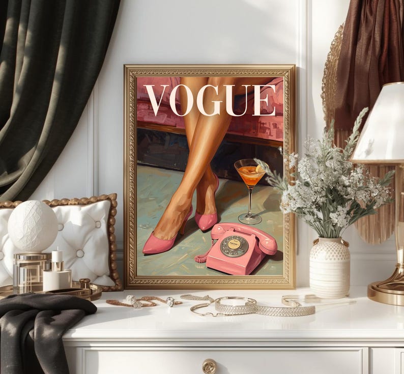 May include: A framed wall art print featuring the word VOGUE in white capital letters. The illustration depicts a pair of legs in pink high-heeled shoes, a martini glass, and a vintage pink rotary telephone on a light green floor surface.