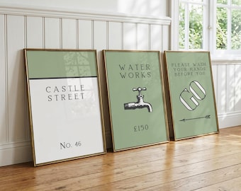 May include: Three framed rectangular wall art prints with sage green and white backgrounds. The first print reads Castle Street No. 46. The second print features a water faucet illustration with the text Water Works and £150. The third print says Please Wash Your Hands Before You Go with an arrow.