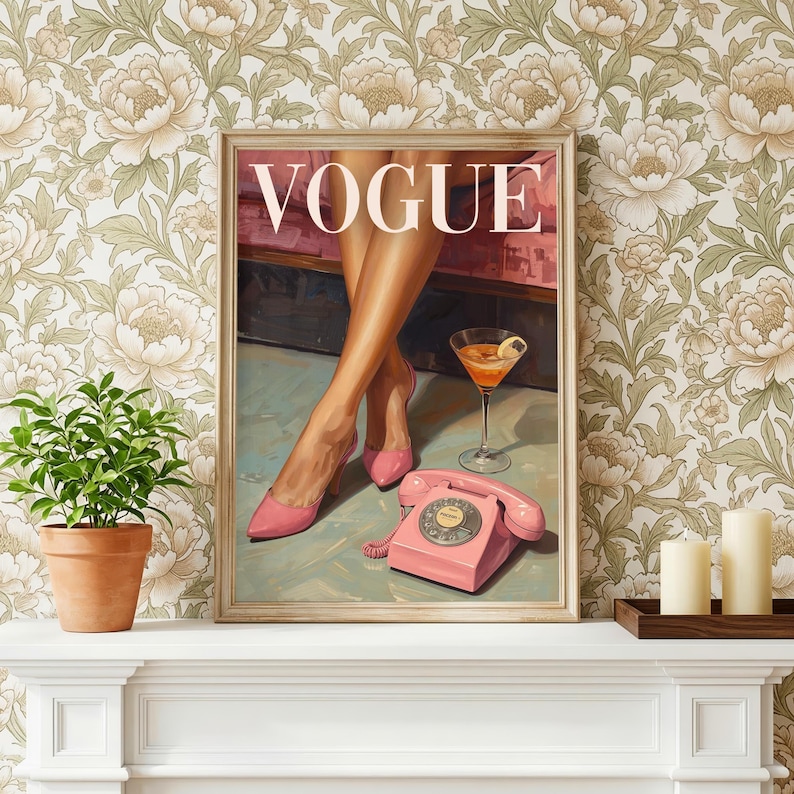 May include: A framed wall art print featuring the word VOGUE in white capital letters. The illustration depicts a pair of legs in pink high-heeled shoes, a glass of orange cocktail, and a pink rotary telephone on a light blue surface.