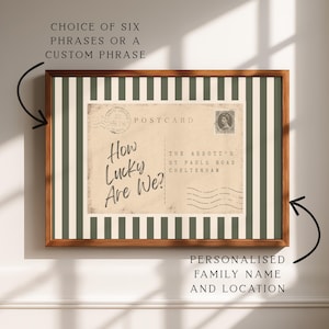 May include: Framed vintage-style postcard print with the text "How Lucky Are We?" and the location "The Abbott's, St Pauls Road, Cheltenham." The print is set against a green and white striped background and framed in a brown wooden frame.