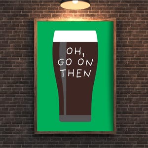 Puede incluir: Un cuadro enmarcado con una pinta de cerveza oscura y el texto blanco "OH, GO ON THEN". La cerveza es marr&oacute;n con espuma blanca, sobre un fondo verde. El marco es marr&oacute;n y el fondo es una pared de ladrillos.