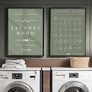 Op de afbeelding: Twee saliegroene wandposters met witte tekst en afbeeldingen. De linker poster toont "OPEN 24 HOURS LAUNDRY ROOM SELF SERVICE" met een kledinghanger en wasknijper. De rechter poster is een "LAUNDRY GUIDE" met diverse wasvoorschrift-symbolen.
