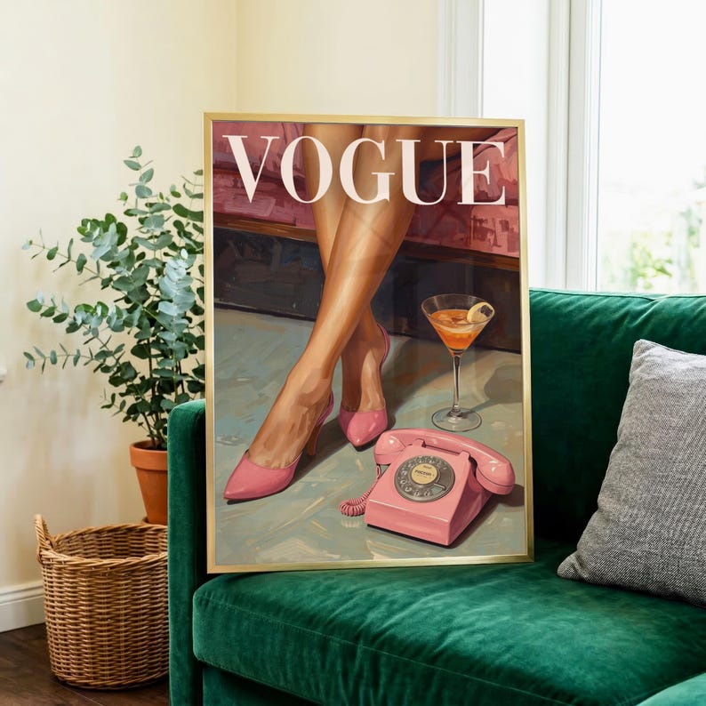May include: A framed wall art print featuring the word VOGUE in white capital letters. The illustration depicts a pair of legs in pink high-heeled pumps, a martini glass with an orange drink, and a vintage pink rotary telephone on a floor.