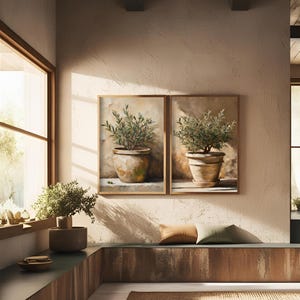 May include: Two framed paintings of potted olive trees with a brown background. The paintings are hung on a light brown wall.