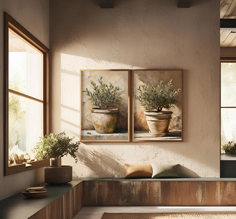 May include: Two framed paintings of potted olive trees with a brown background. The paintings are hung on a light brown wall.
