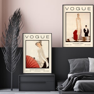 Może przedstawiać: Dwie oprawione grafiki z okładkami magazynu Vogue z ilustracjami mody vintage. Lewa grafika przedstawia osobę z czerwonym parasolem, prawa osobę w białej sukni z czerwonym szalem. Obie zawierają napis VOGUE.