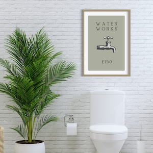 May include: A framed wall art print featuring a sage green background with the black text WATER WORKS above a black and white illustration of a water faucet and the text &pound;150 below it, all enclosed in a simple light brown wooden frame.
