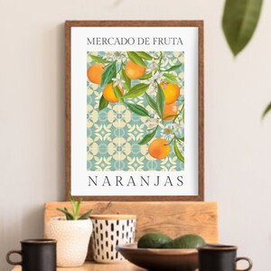 May include: A framed print with a vintage illustration of orange blossoms and fruit on a blue and white tiled background. The text "Mercado de Fruta Naranjas" is printed below the illustration.