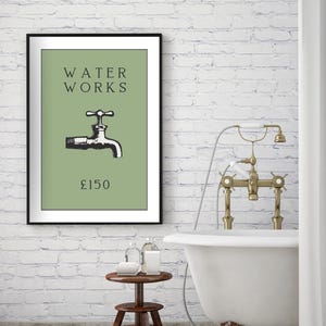 May include: A framed wall art print featuring a sage green background with the black text WATER WORKS, a black illustration of a water faucet, and the text &pound;150 at the bottom. The print is displayed in a thin black frame on a white brick wall.