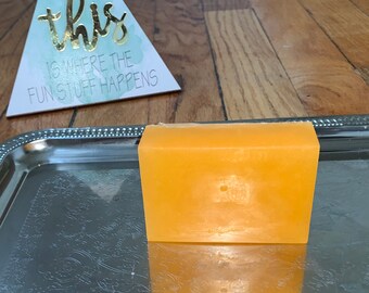 May include: A rectangular bar of bright orange soap on a silver tray.