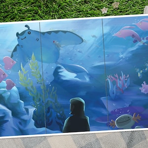 May include: A vibrant underwater scene illustration featuring a large blue manta ray, pink fish, and a person looking at the marine life. The artwork has a cartoonish style with coral and seaweed.