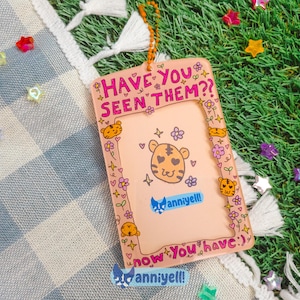 May include: A pink rectangular tag with the text "HAVE YOU SEEN THEM??" and "now You have:)". The tag features a tiger illustration, flowers, and the brand name "anniyell!". The tag is hanging on a string, surrounded by star-shaped decorations.