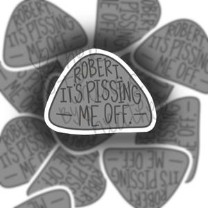 May include: A collection of gray, triangular stickers with the text "ROBERT IT'S PISSING ME OFF" in a bold, sans-serif font. The stickers have a white border and a distressed, textured appearance.