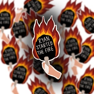 May include: A black and red sticker with the text "Ryan Started The Fire" on a black paddle with flames around it.