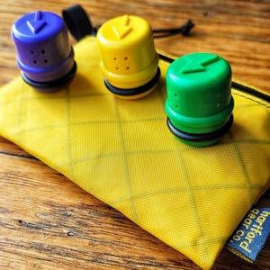 May include: Three colourful plastic caps with a lightning bolt design and air holes. The caps are in a yellow pouch with a blue tag that says "Moth & Bear Co."