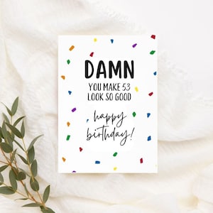 Op de afbeelding: Witte kaart met zwarte tekst die "DAMN YOU MAKE 53 LOOK SO GOOD happy birthday!" luidt, met kleurrijk confetti verspreid rond de tekst.