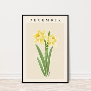 Può includere: Una stampa artistica incorniciata con un'illustrazione ad acquerello di due narcisi gialli e foglie verdi. La parola "DECEMBER" è stampata in nero in alto. L'opera d'arte ha uno sfondo beige ed è incorniciata in nero.