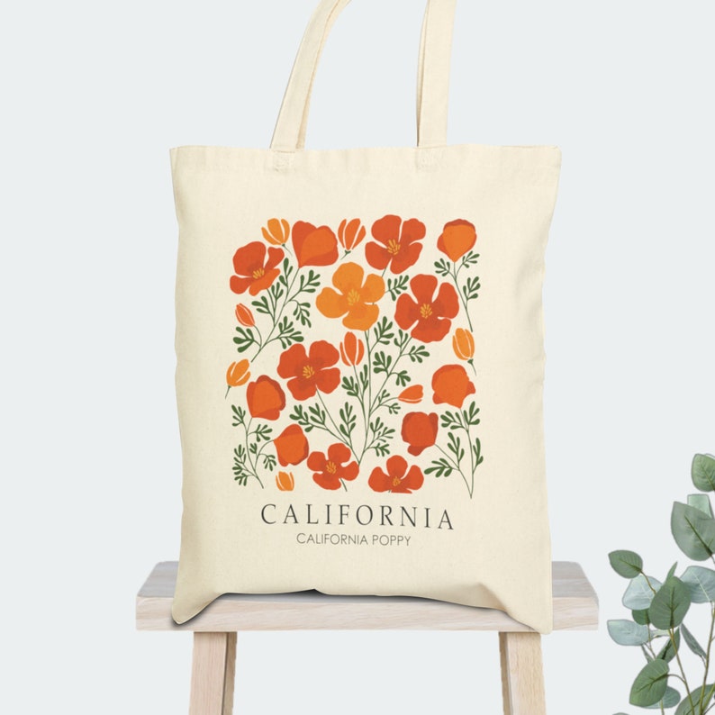 May include: A beige tote bag with a design of orange and yellow California poppies on a white background. The text "CALIFORNIA" and "CALIFORNIA POPPY" is printed in black at the bottom of the bag.