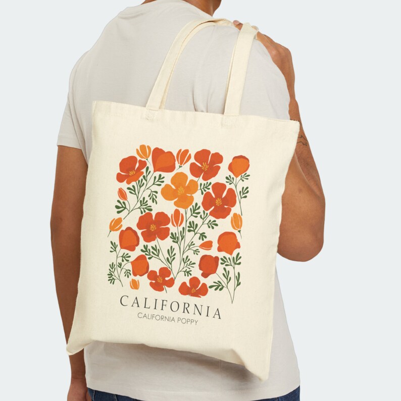 May include: A beige tote bag with a floral design featuring orange and red California poppies. The bag has the text "CALIFORNIA" and "CALIFORNIA POPPY" printed on it.