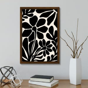 May include: Black and white floral print framed wall art with a brown frame. The print features stylized flowers and leaves.