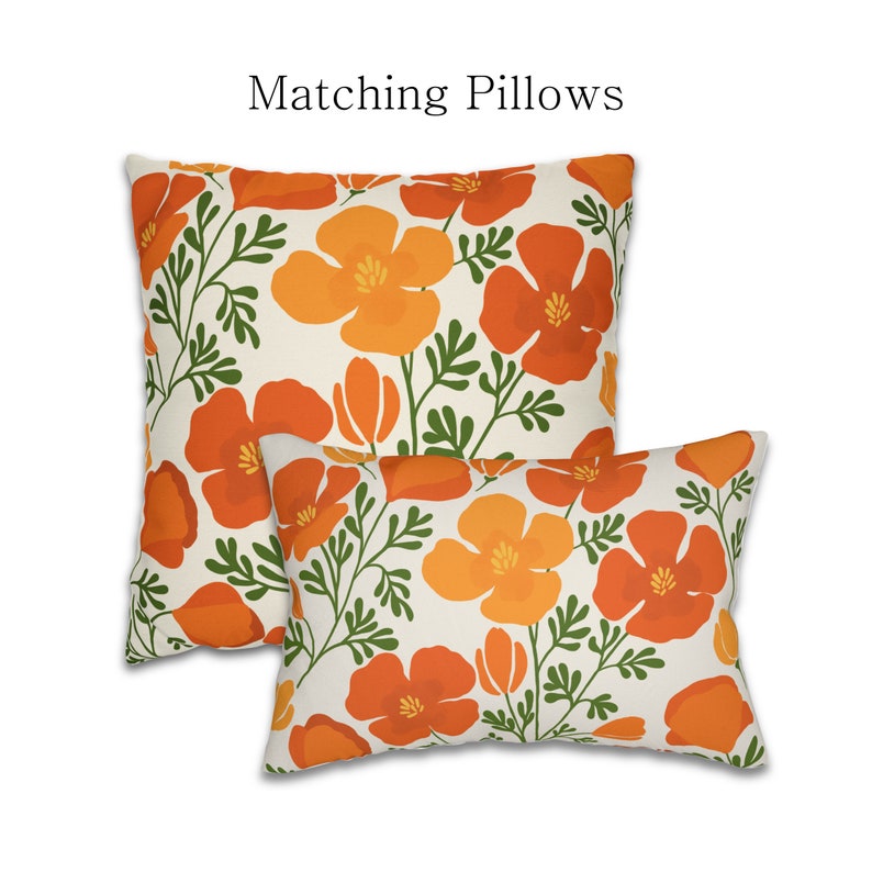Pu&ograve; includere: Due cuscini decorativi con motivo floreale. I cuscini presentano fiori arancioni e gialli con steli e foglie verdi su sfondo crema. Il testo "Matching Pillows" &egrave; sopra i cuscini.