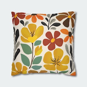 May include: Square throw pillow with a floral pattern. The design features large yellow, orange, and brown flowers with green leaves and black accents on a cream background. The pillow is a decorative home accent.