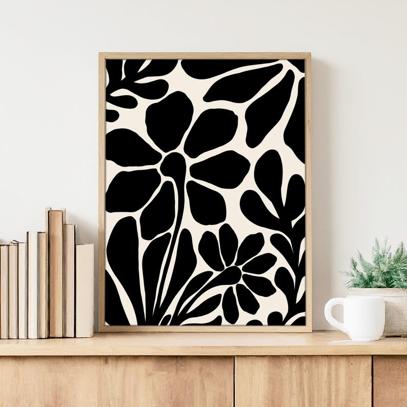 May include: Black and white abstract floral print art print in a wooden frame. The print features stylized flowers and leaves.